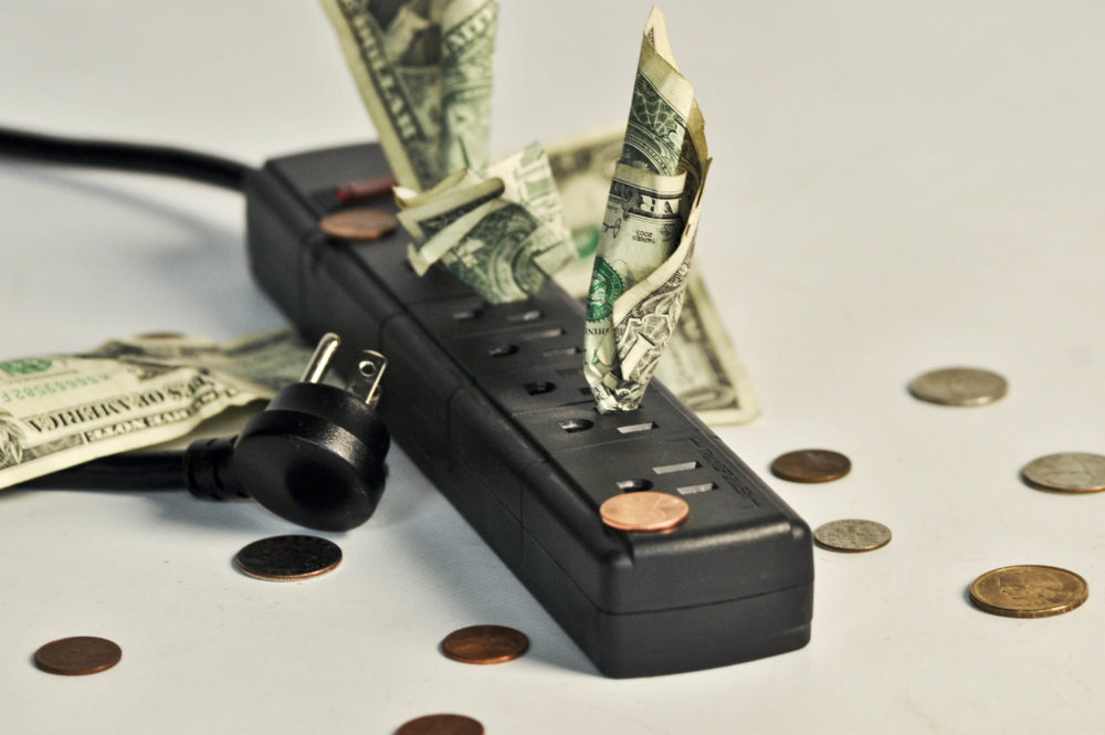 photo illustration of bills and coins scattered near a multi-outlet power extension cord