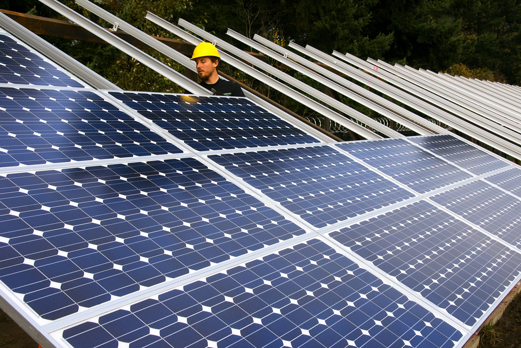 A person in a hard hat assembles solar panels.