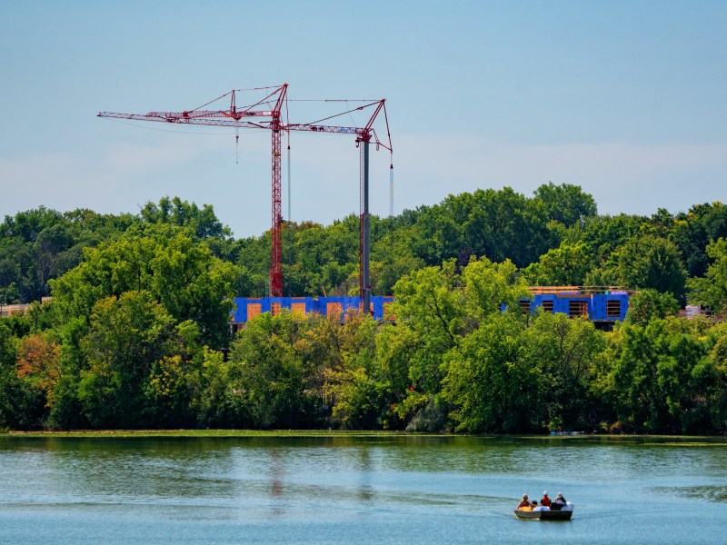 Construction cranes tower over a new building development project in Robbinsdale, Minnesota, as seen from across Crystal Lake.