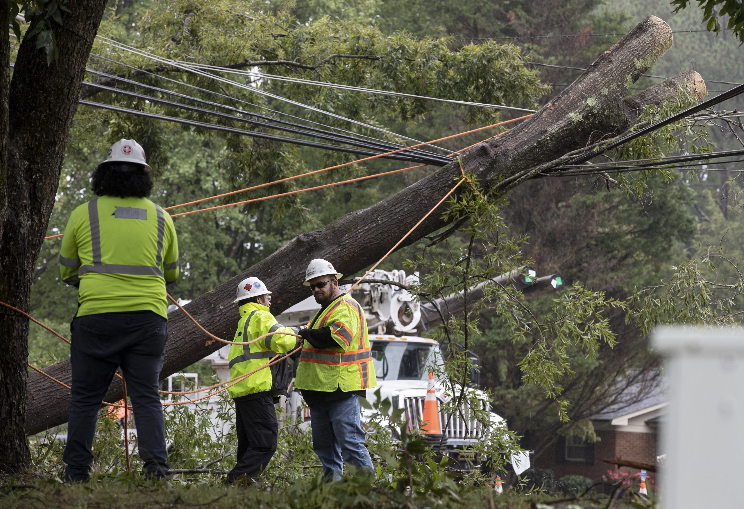 Crews work to clear a tree that fell on power lines on Cole Mill Road following Tropical Storm Ian on Saturday, Oct. 1, 2022, in Durham, N.C.