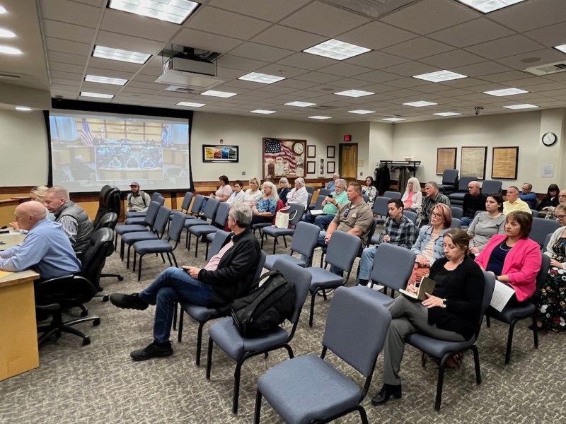 A few rows of seats in a county office are about half full.