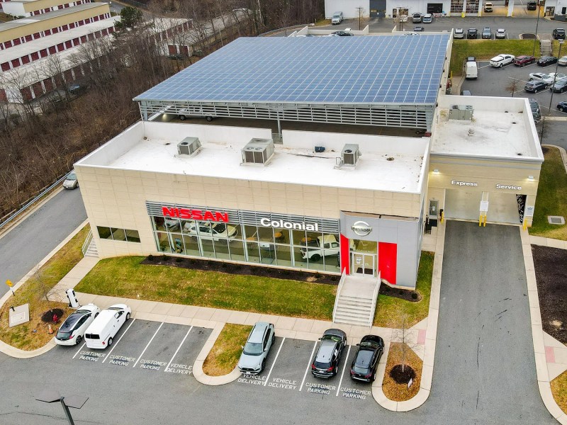 Aerial photo of a car dealership whose roof is nearly completely covered in solar panels.