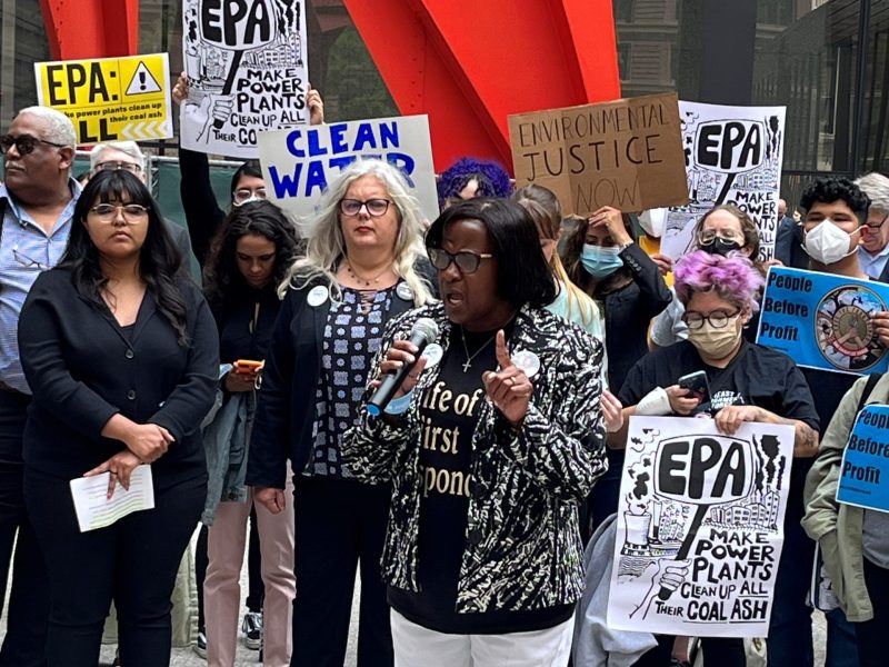 Betty Johnson speaks into a microphone, surrounded by rally-goers.