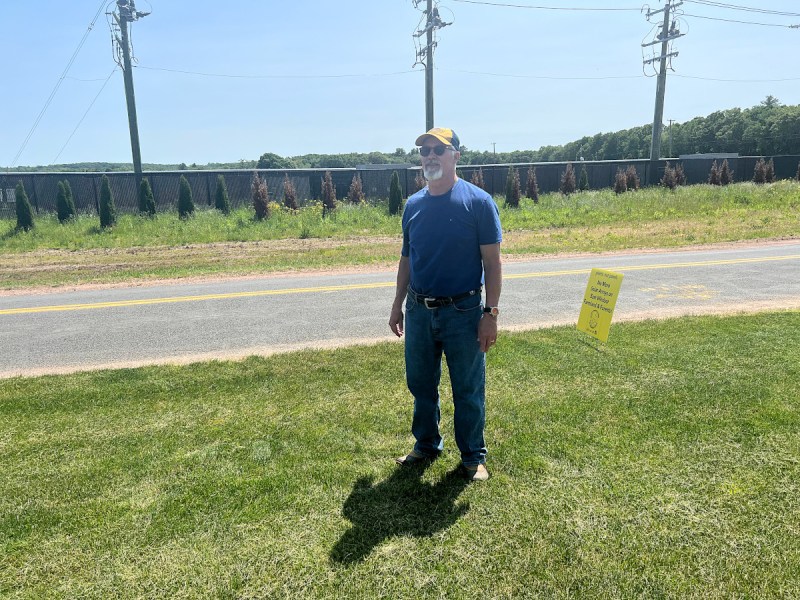 Dana Van Steenburgh stands across the street from a solar array