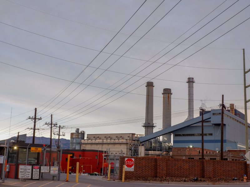 A power plant with three smokestacks and power lines running to it.