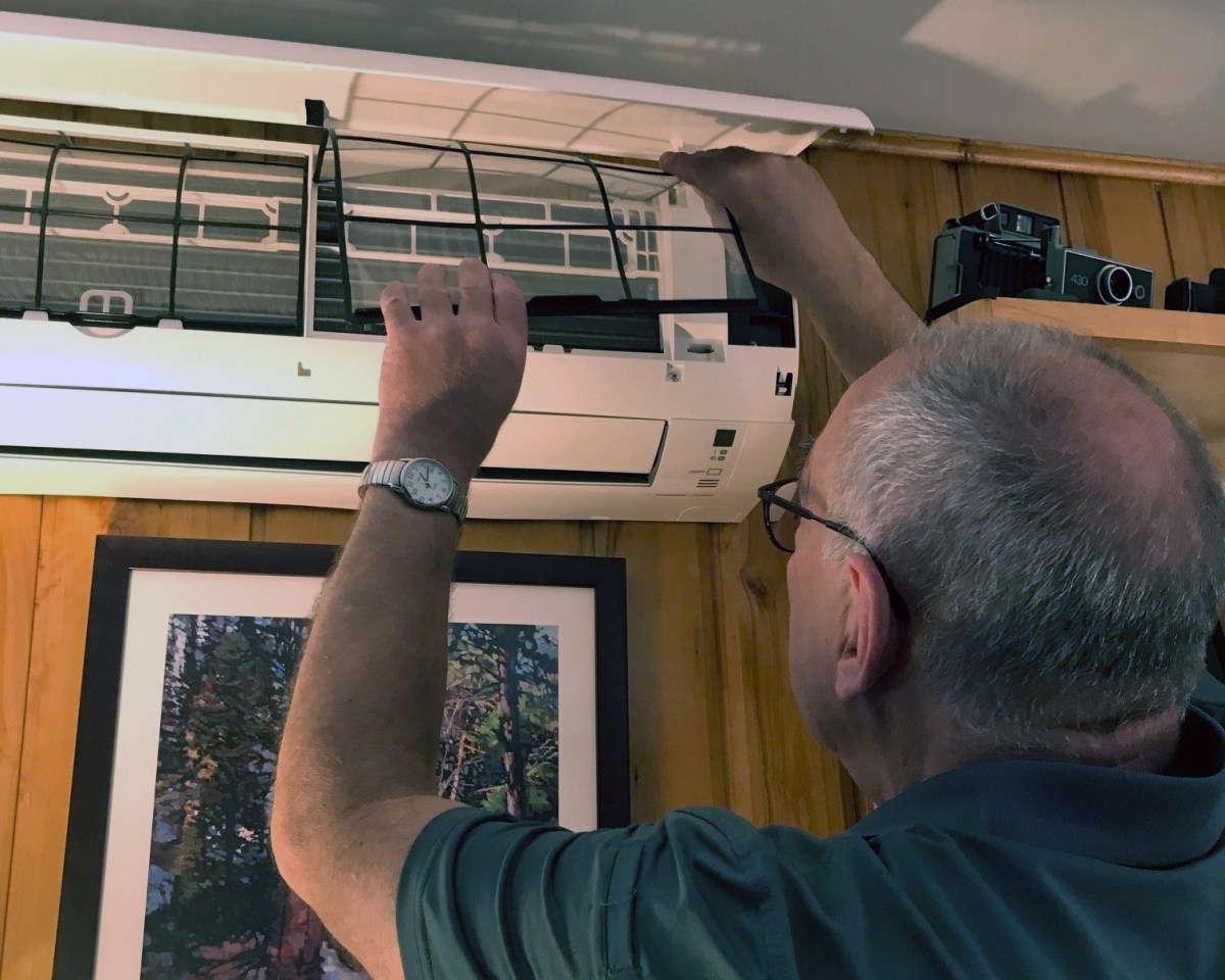 Michael Overend adjusts the indoor unit of his home's heat pump.