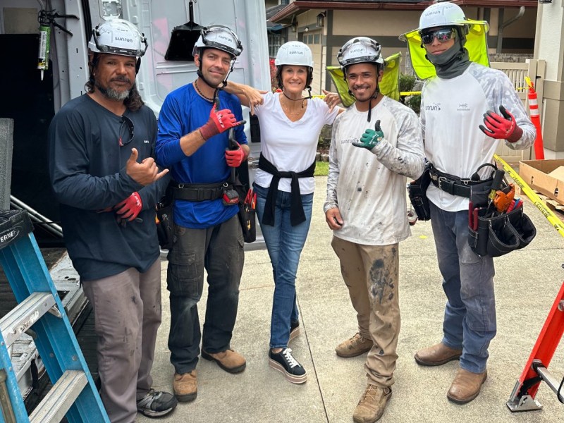 Sunrun CEO Mary Powell poses with workers on a job site in Hawaii.