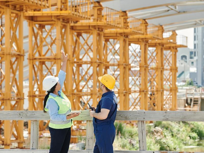 I man and woman in hard hats talking at a construction site.