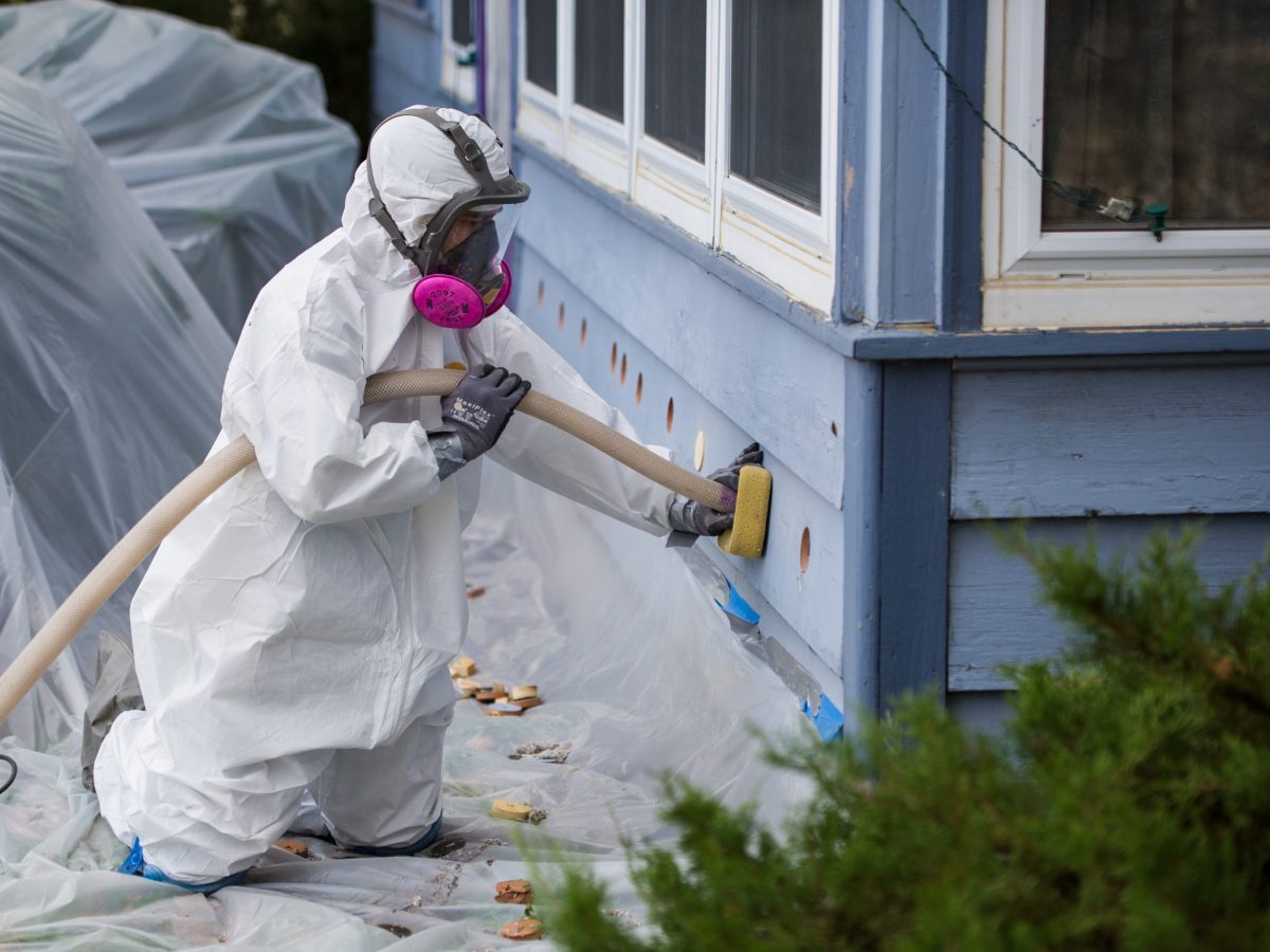 A weatherization worker injects insulation into the exterior walls of a home.